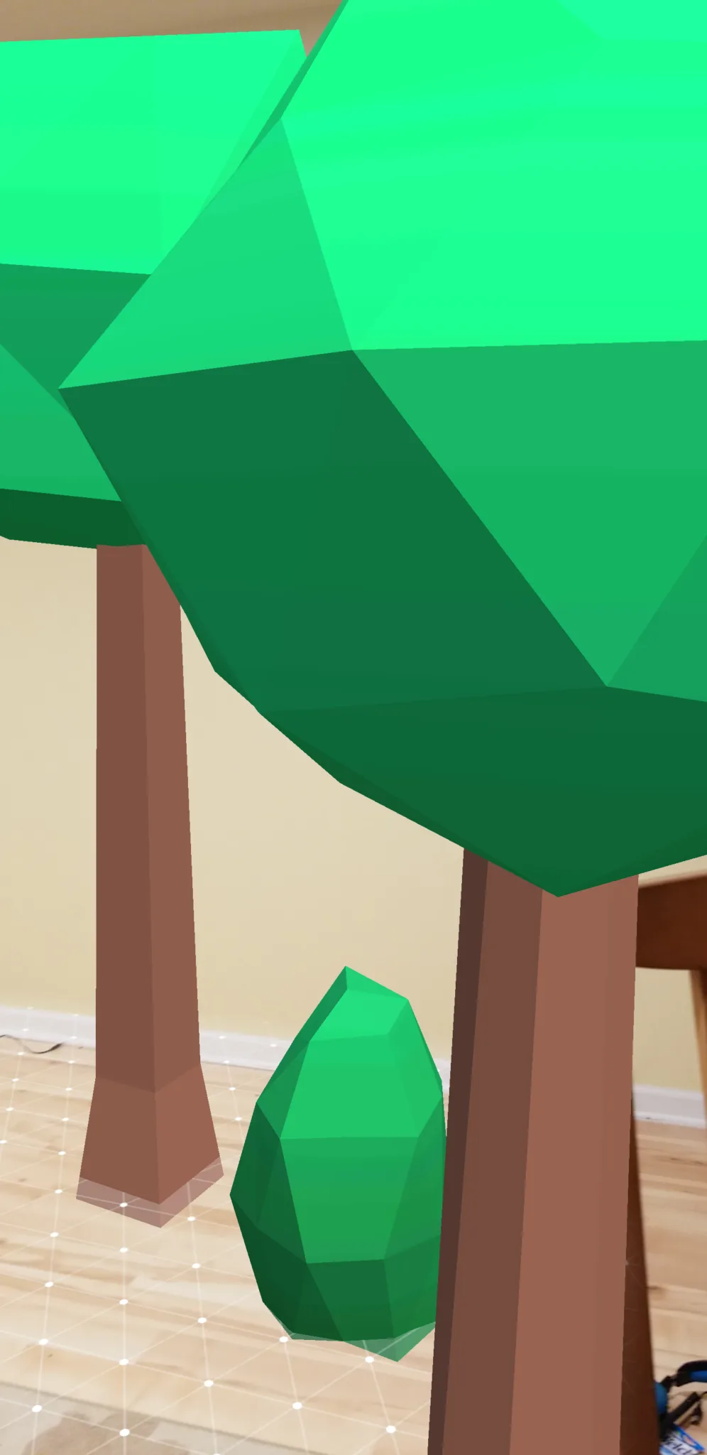 Virtual low-poly trees anchored to a real surface, viewed through the phone camera
